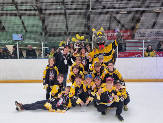Photo de l'équipe du groupe U11 sur la glace, avec la mascotte des Dragons de Rouen